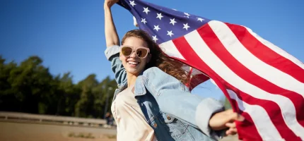jeune fille joyeuse avec un drapeau americain au vent